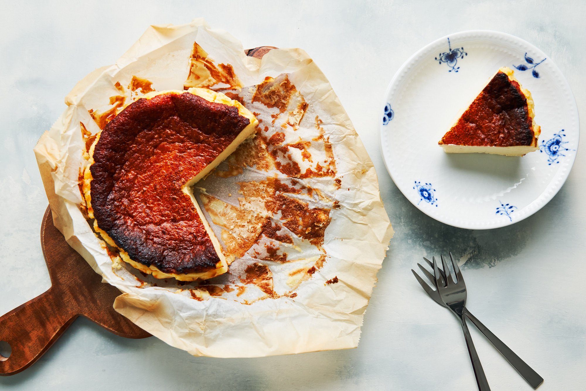 Burnt Basque Cheesecake wrapped in parchment paper on a wooden cutting board.