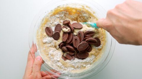 Mixing chocolate chunks into banana bread batter.