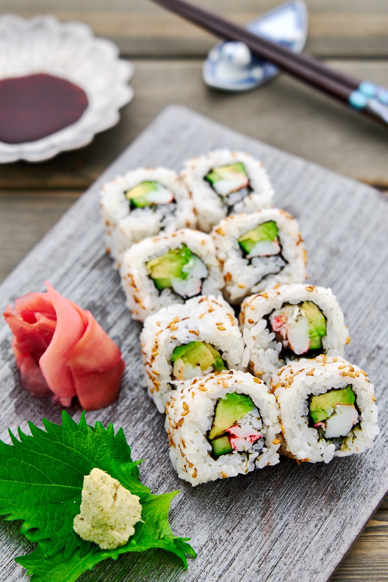 Closeup of a plate of homemade California rolls filled with crab, avocado and cucumber wrapped in tangy sushi rice and nori.