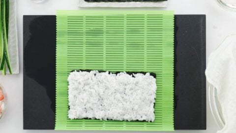 Rice evenly spread across nori for uramaki style sushi roll.