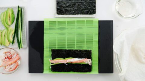 Ingredients for California Roll on a sushi mat.