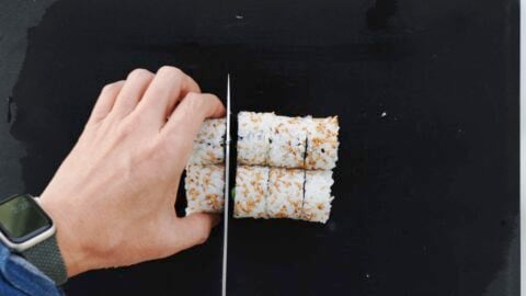 Cutting California Roll into bite-sized pieces.