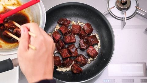 Browning beef in a frying pan that's been marinated with black pepper sauce.
