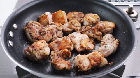 Browning black pepper chicken in a frying pan.