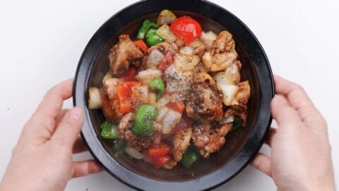 Bowl of black pepper chicken garnished with freshly cracked black pepper.