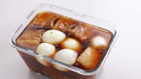 Soaking braised pork belly kakuni with soft boiled eggs in a glass container.