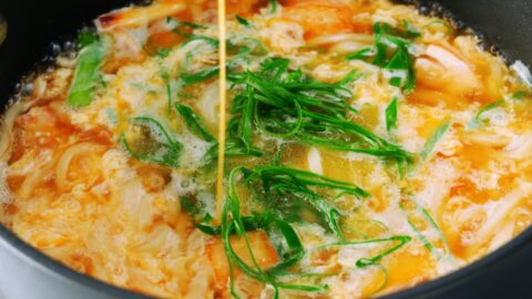 Drizzling egg into chicken udon noodles.