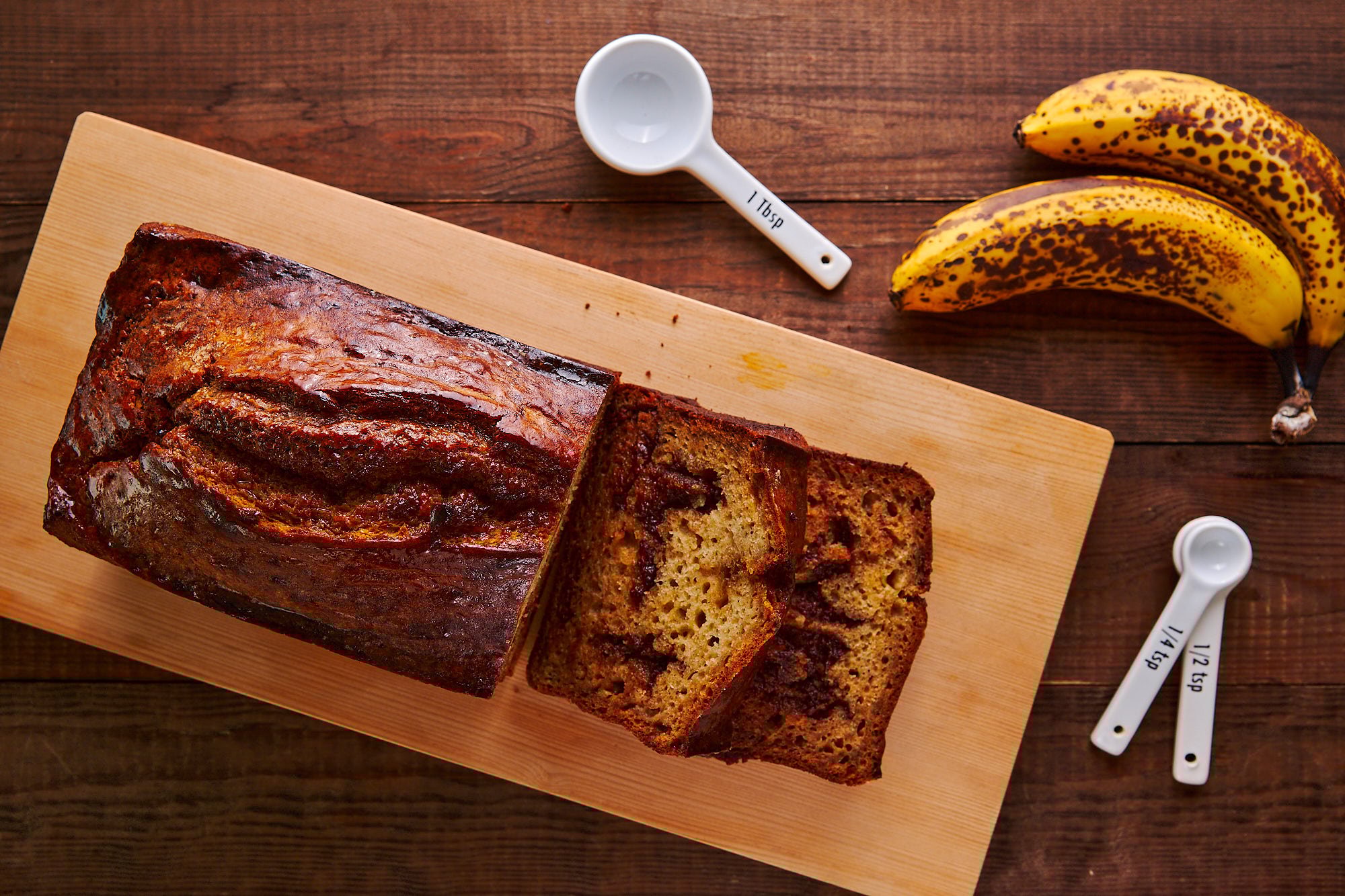 Slices of chocolate chunk banana bread on a wooden cutting board.