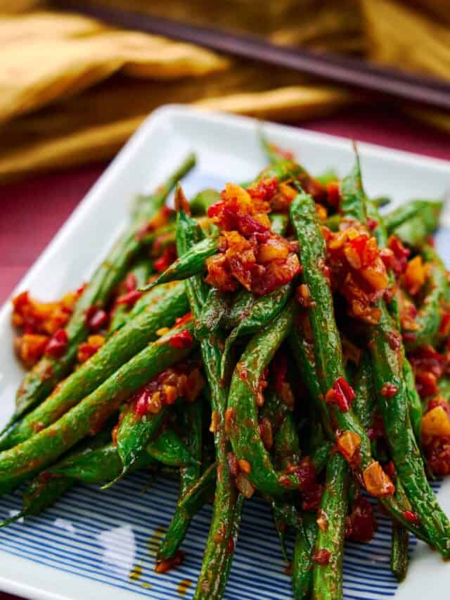 A plate of vibrant green beans stir-fried with chili garlic sauce. An easy 3 ingredient Chinese stir fry.