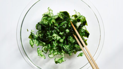Cucumber and wakame come together in the bowl, tossed with chopsticks until evenly coated in dressing.