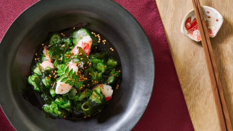 A finished bowl of crab sunomono rests on a crimson cloth, garnished and ready to refresh the palate.