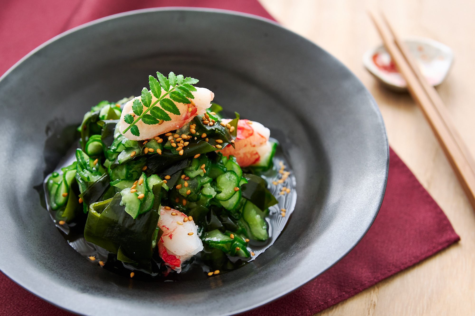 Plated sunomono salad with crab and sesame seeds glows under soft light, inviting with its glossy textures and vivid greens.