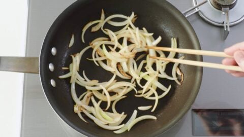 Stir-frying sliced onions for gyudon.