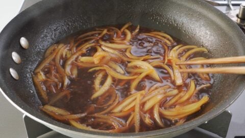 Simmering sliced onions in gyudon sauce.
