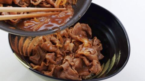 Assembling Gyudon by serving on top of a bowl of rice.