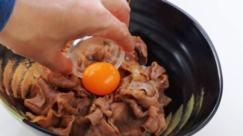Placing a golden egg yolk on top of a beef bowl.