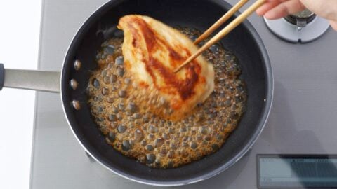 Glazing chicken breast with teriyaki sauce.
