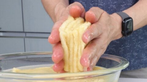 Squeezing excess water and oil from fried tofu wrappers.