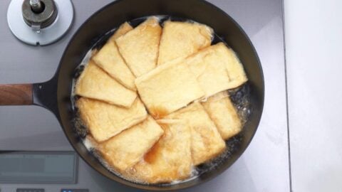 Making inari wrappers by seasoning fried tofu pockets.