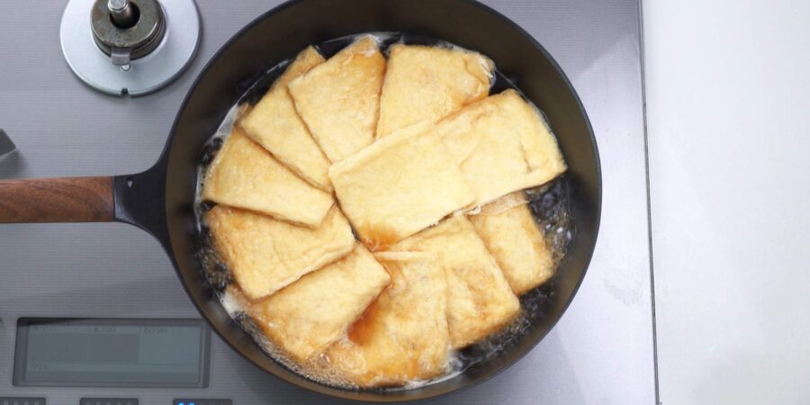 Making inari wrappers by seasoning fried tofu pockets.