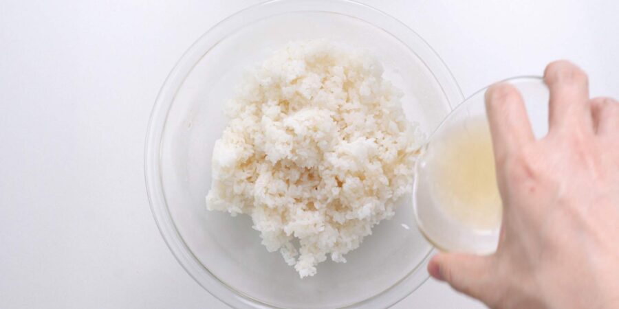 Pouring sushi vinegar over rice.