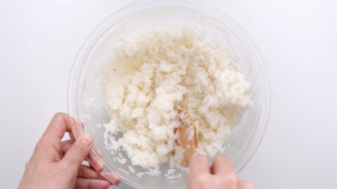 Mixing sushi seasoning into rice.