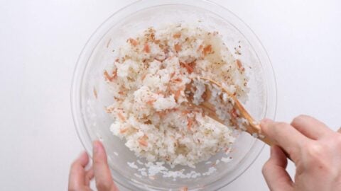 Mixing pickled ginger and toasted sesame seeds into rice.