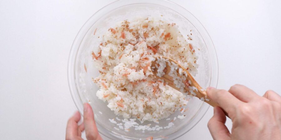 Mixing pickled ginger and toasted sesame seeds into rice.