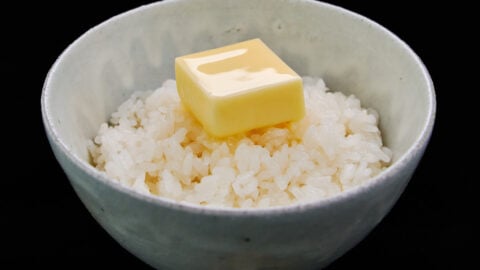 A golden pat of butter nestled on top of freshly cooked, hot Japanese rice, gently beginning to melt.