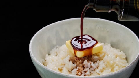 A savory drizzle of soy sauce pouring onto melting butter and hot rice, creating the ultimate bowl of comforting Japanese butter rice.