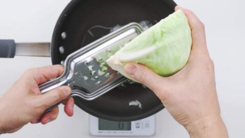 Grating cabbage and onions into a pan.
