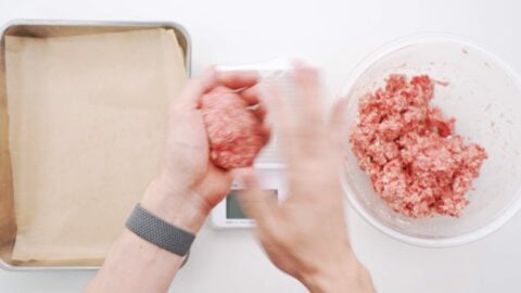 Removing air from hamburg patties with hands.