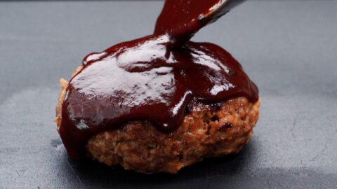 Pouring Japanese demi-glace sauce over a hamburg steak.