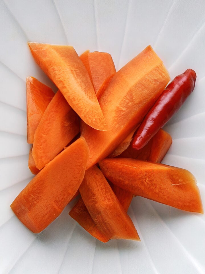 Overhead shot of Japanese pickled carrots with a dried chili accent—crisp, savory, and vibrant with soy sauce sheen and umami-rich depth.