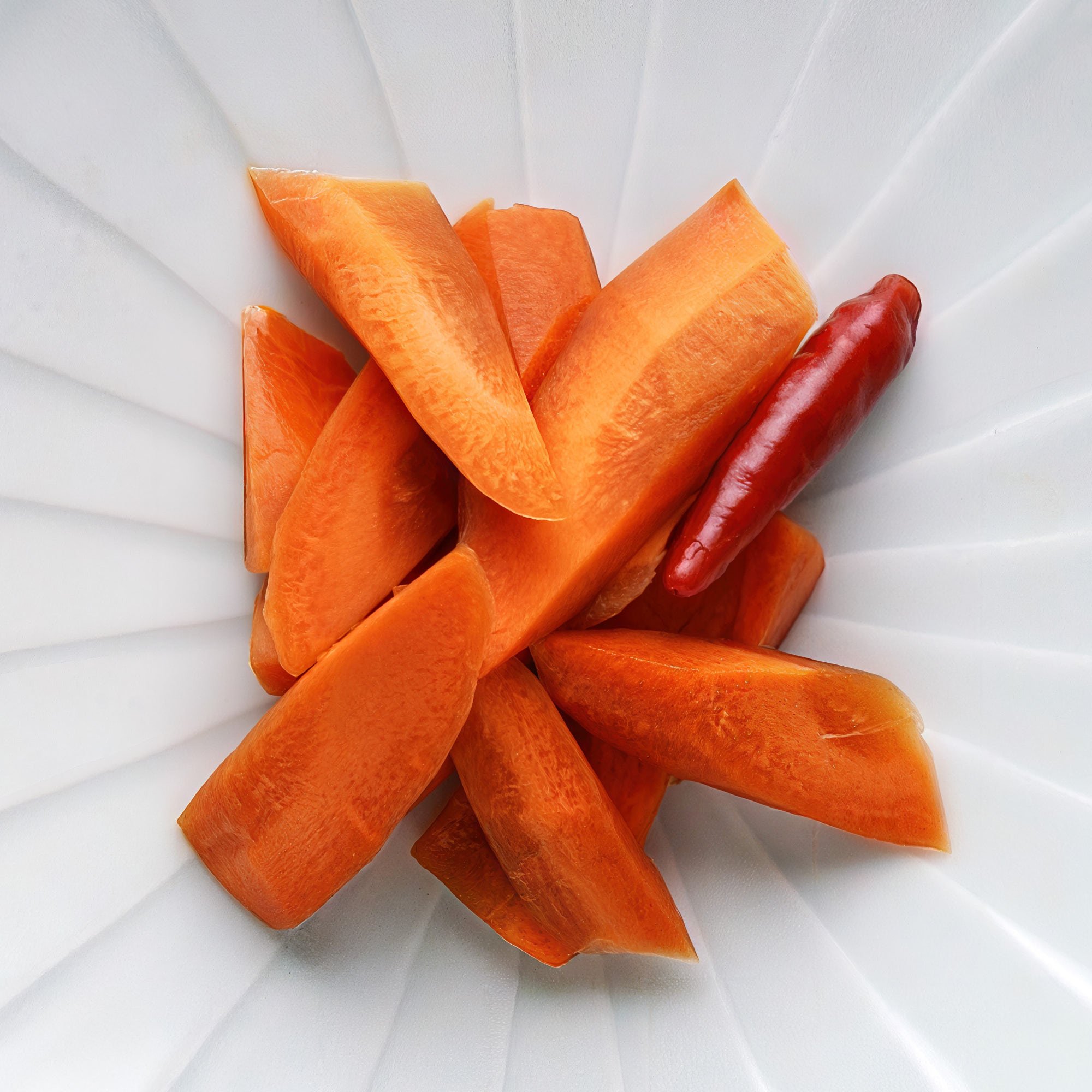 Overhead shot of Japanese pickled carrots with a dried chili accent—crisp, savory, and vibrant with soy sauce sheen and umami-rich depth.