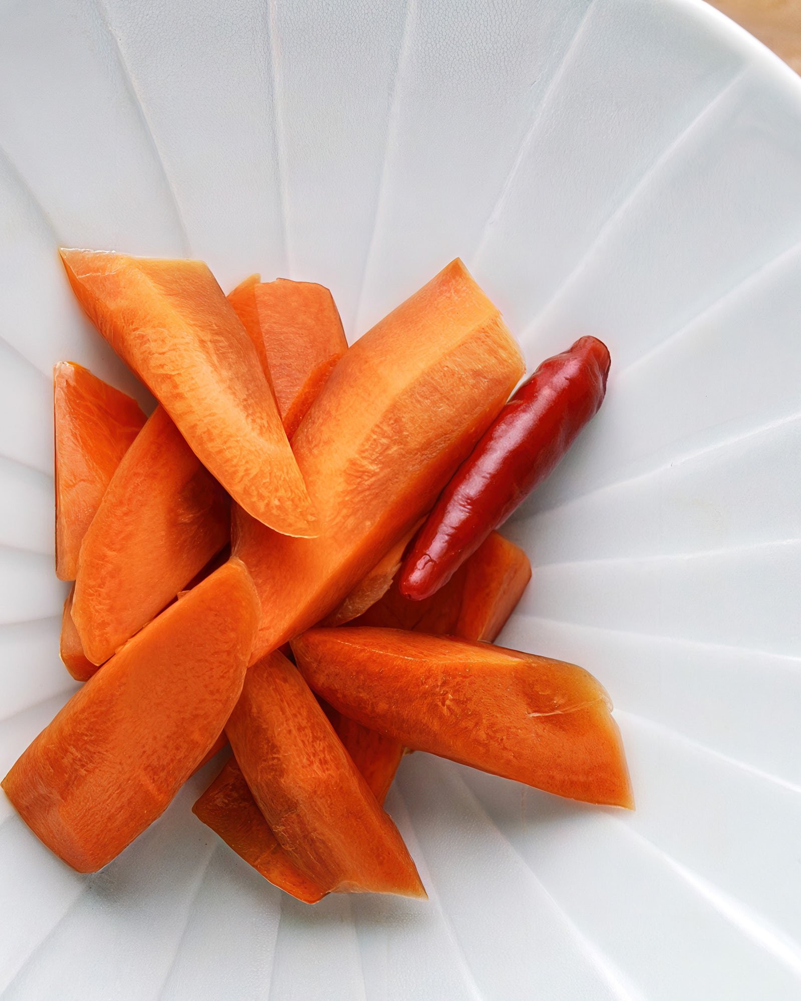 Overhead shot of Japanese pickled carrots with a dried chili accent—crisp, savory, and vibrant with soy sauce sheen and umami-rich depth.