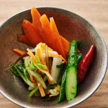 A bowl of three types of Japanese pickles including asazuke, carrot shoyuzuke, and cucumber shiozuke.