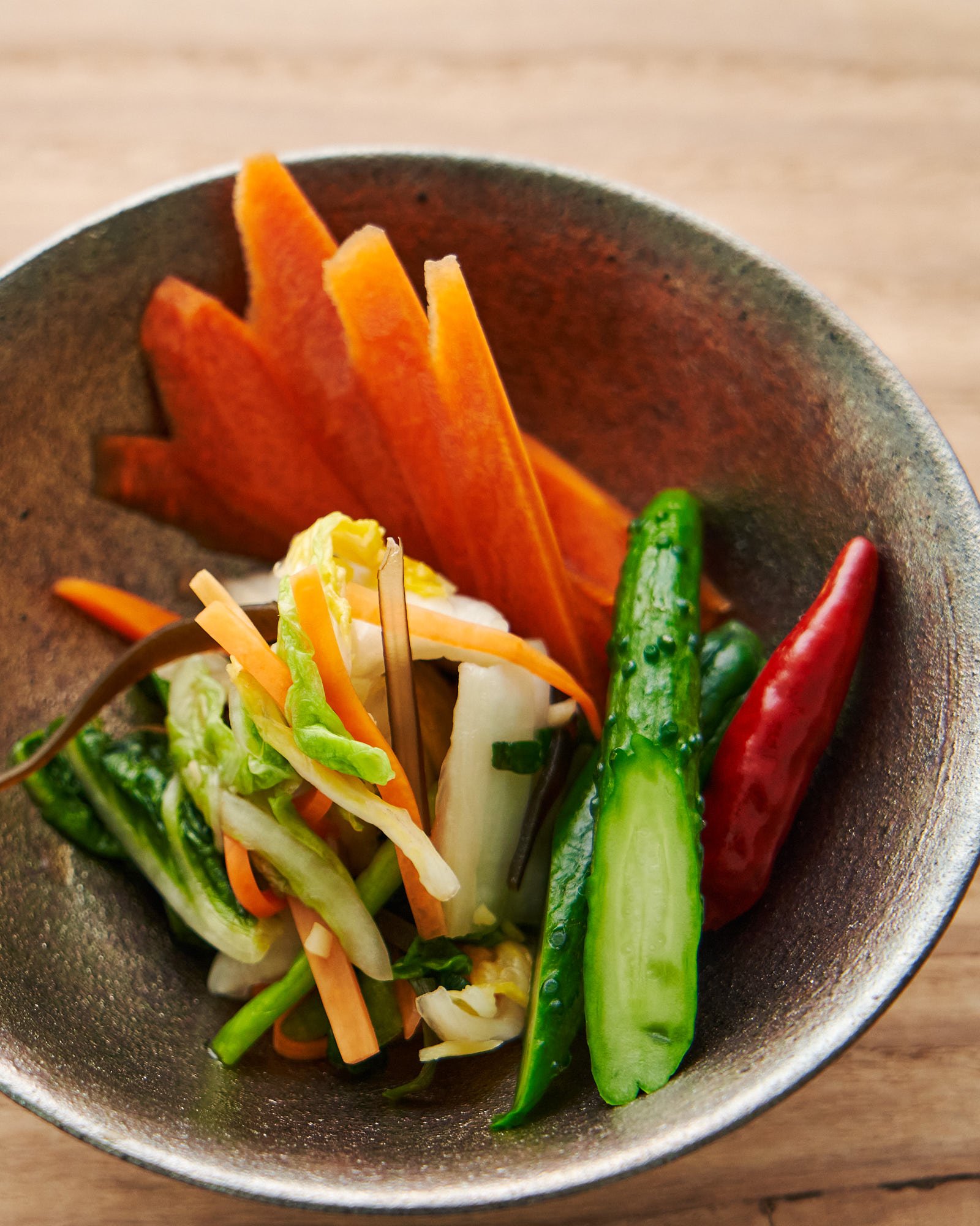 A bowl of three types of Japanese pickles including asazuke, carrot shoyuzuke, and cucumber shiozuke.