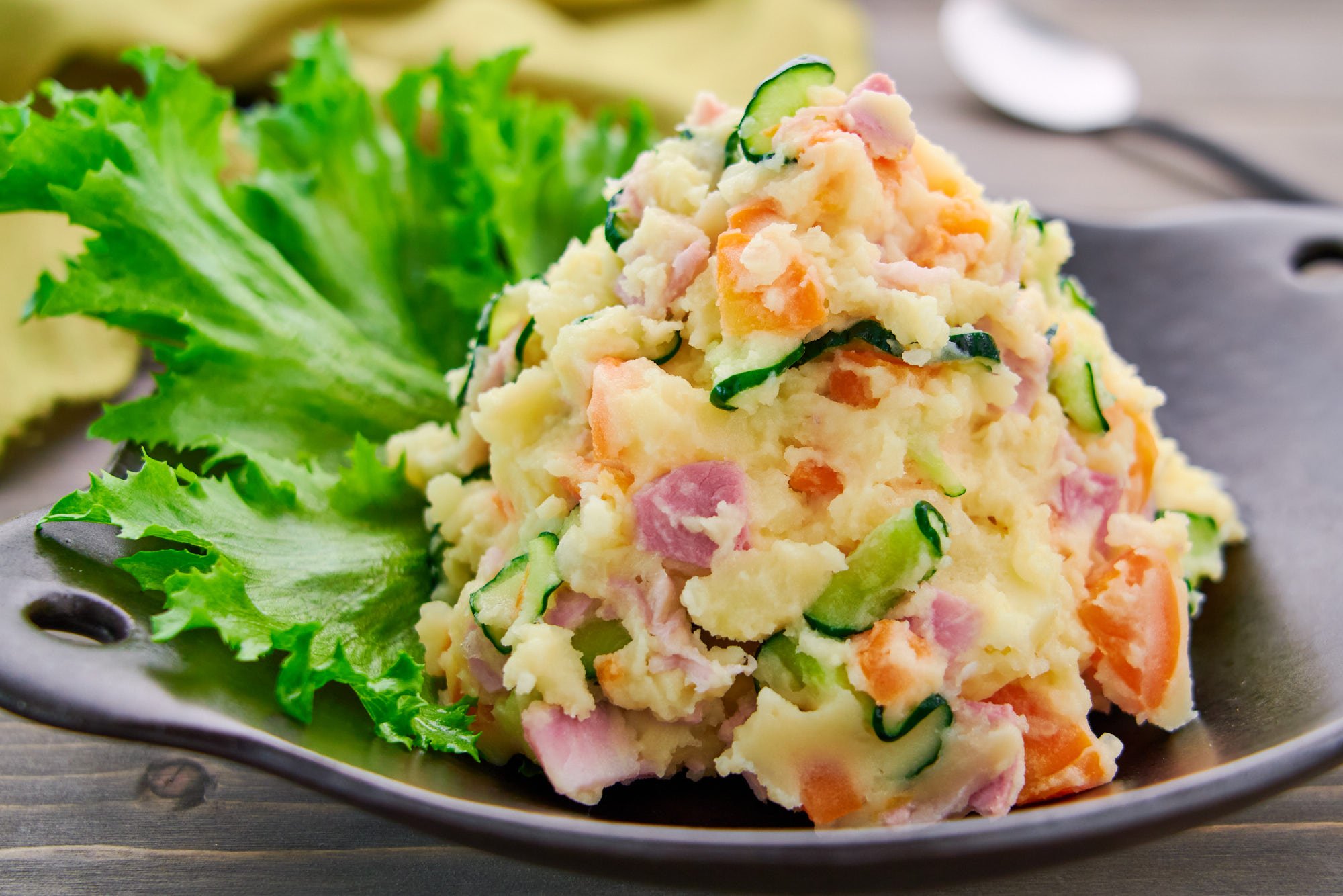 A mound of Japanese Potato Salad brimming with creamy potatoes, savory ham, crunchy cucumbers and sweet carrots.