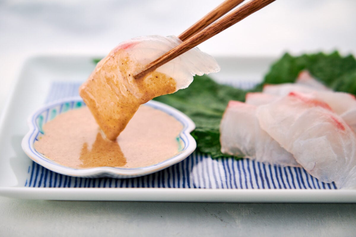 Tai (Sea Bream) sashimi being dipped in Japanese sesame sauce.