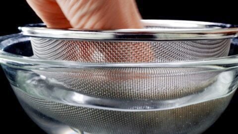Washing rice in water to remove excess starch.