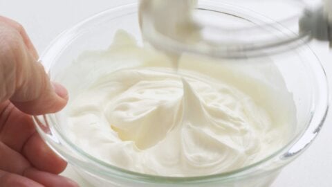 Whipped cream in a glass bowl holding peaks.