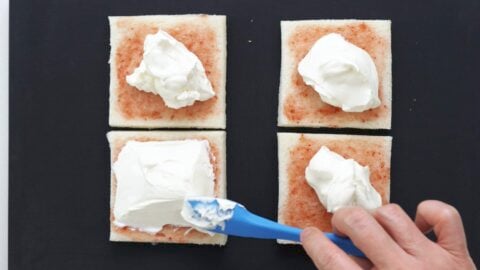 Spreading whipped cream around bread.