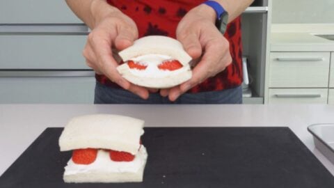 Shaping bread around the strawberry and cream filling.