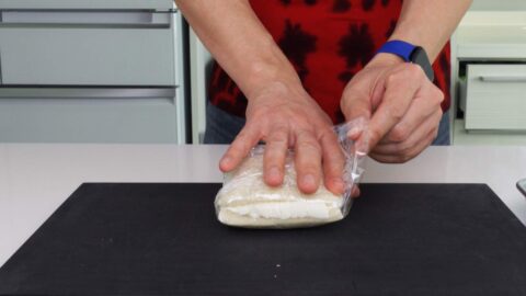 Wrapping strawberry cream sandwich with plastic wrap to set the shape.