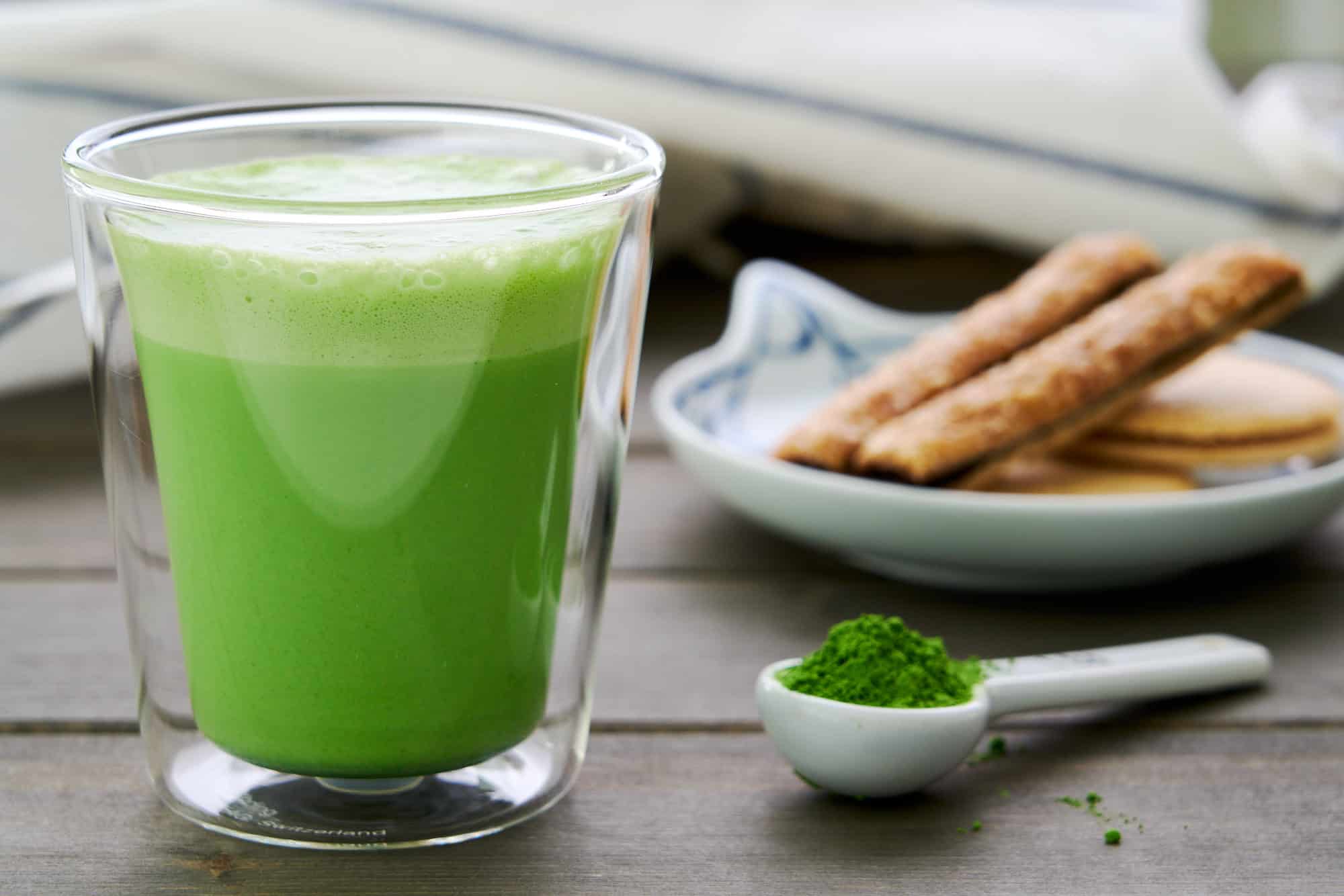 Close-up of Matcha Latte Hot Chocolate in a clear glass mug, showcasing the vibrant green color and creamy foam layer on top.