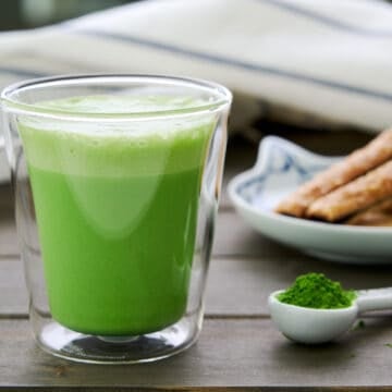 Close-up of Matcha Latte Hot Chocolate in a clear glass mug, showcasing the vibrant green color and creamy foam layer on top.