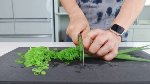 Slicing scallion greens for mazemen topping.
