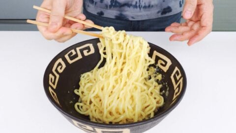 Mixing ramen noodles with scallion oil in a bowl.