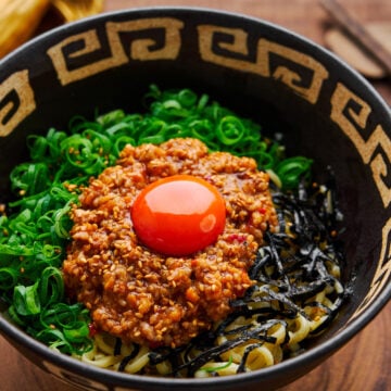 A bowl of spicy mazesoba ramen noodles with scallion oil and spicy pork.